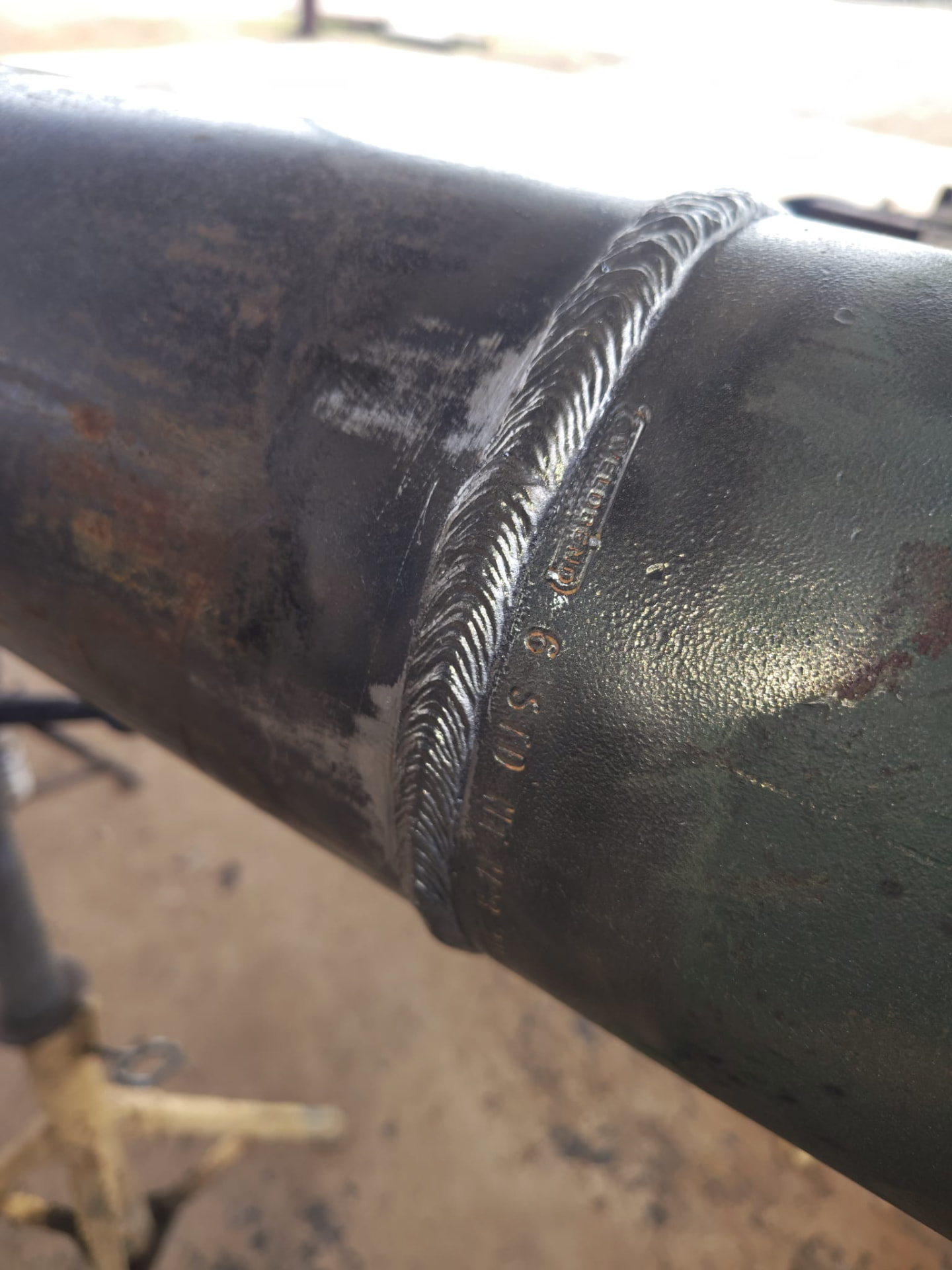 Fabricated green pipeline spool set on jack stands at a tank battery