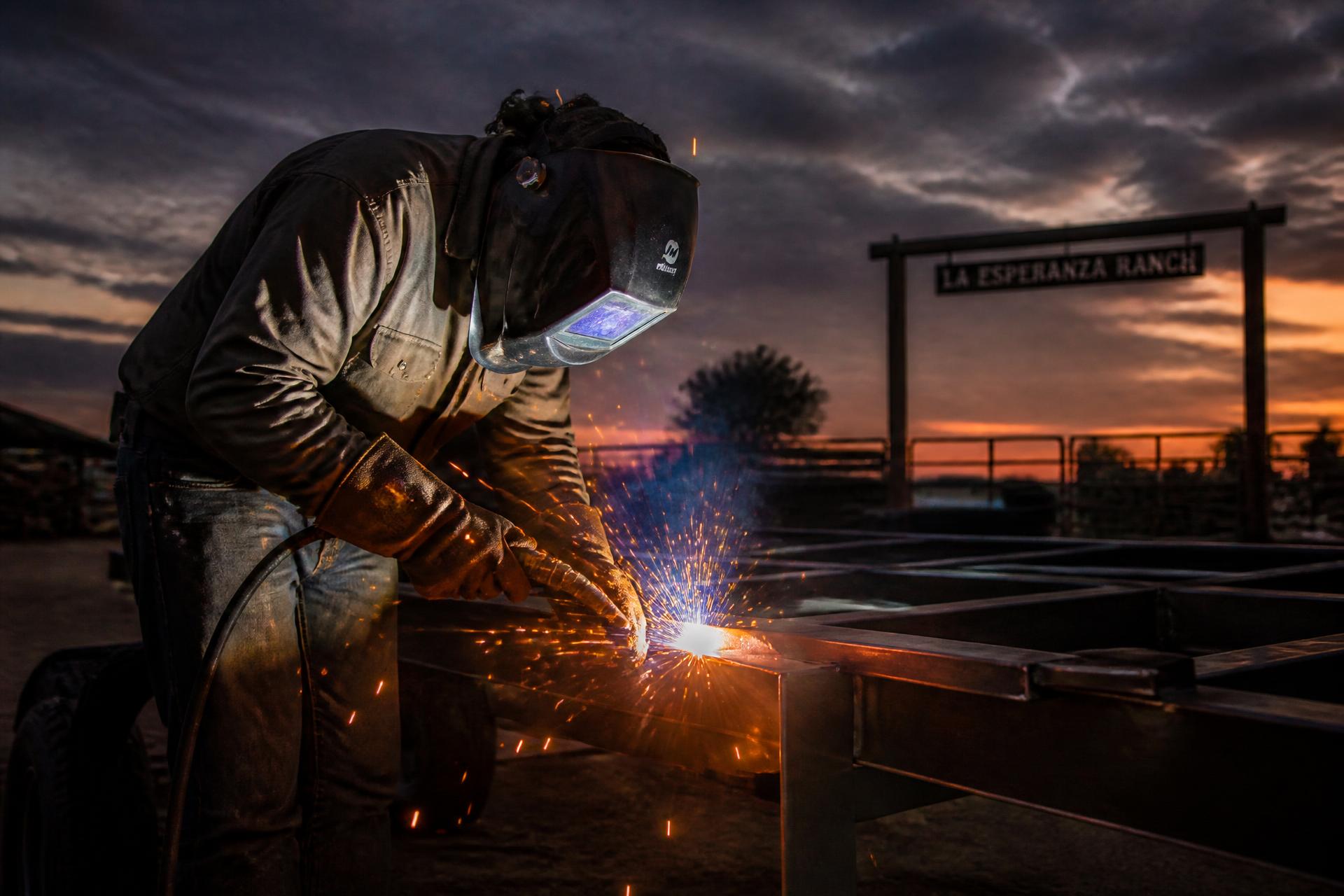 Welder repairing a steel trailer frame at a South Texas ranch